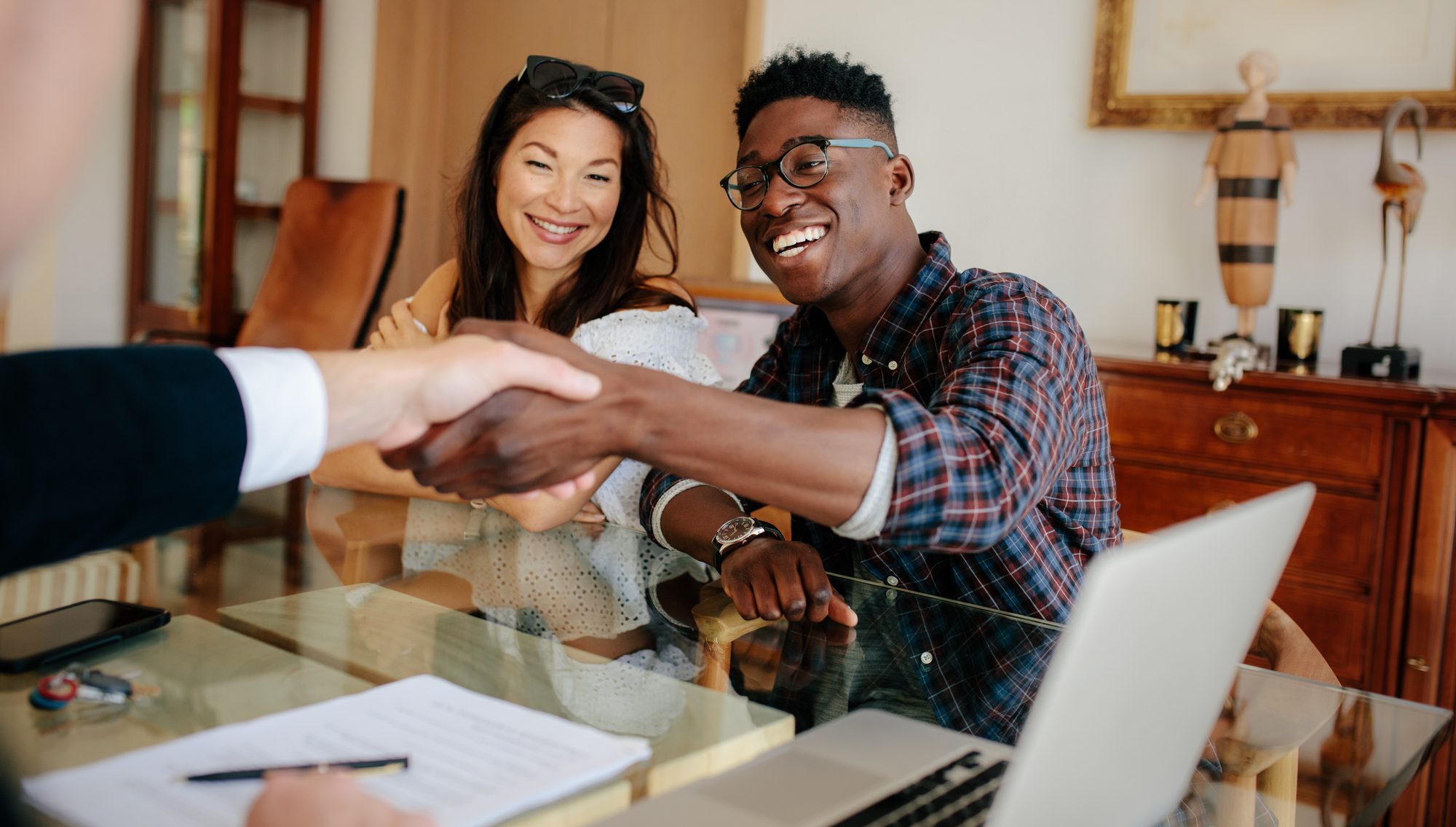 Happy property owners shaking hands with real estate broker after a dea